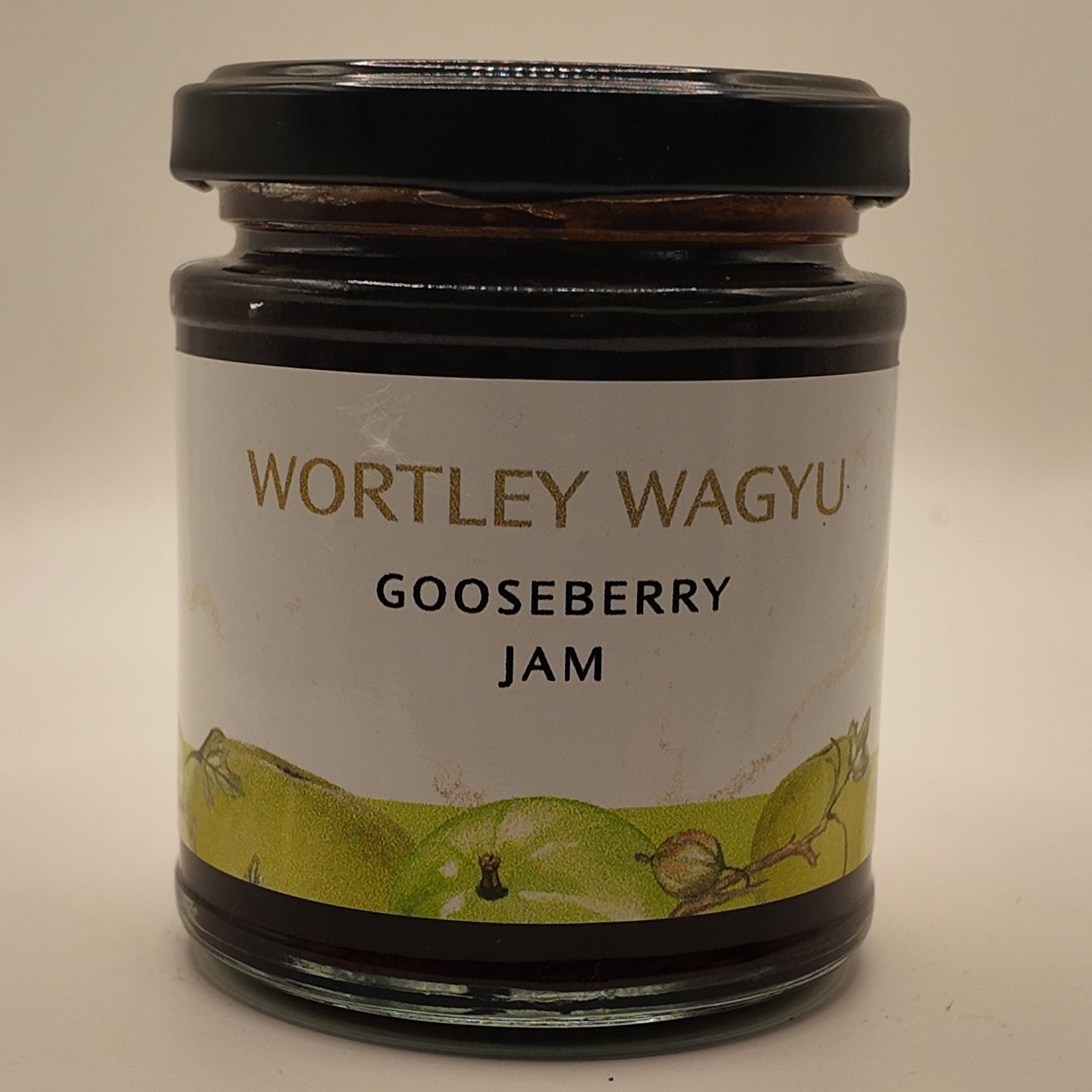 A glass jar of Wortley Wagyu Gooseberry Jam with a black lid and a white label featuring green gooseberry illustrations, set against a plain light background.