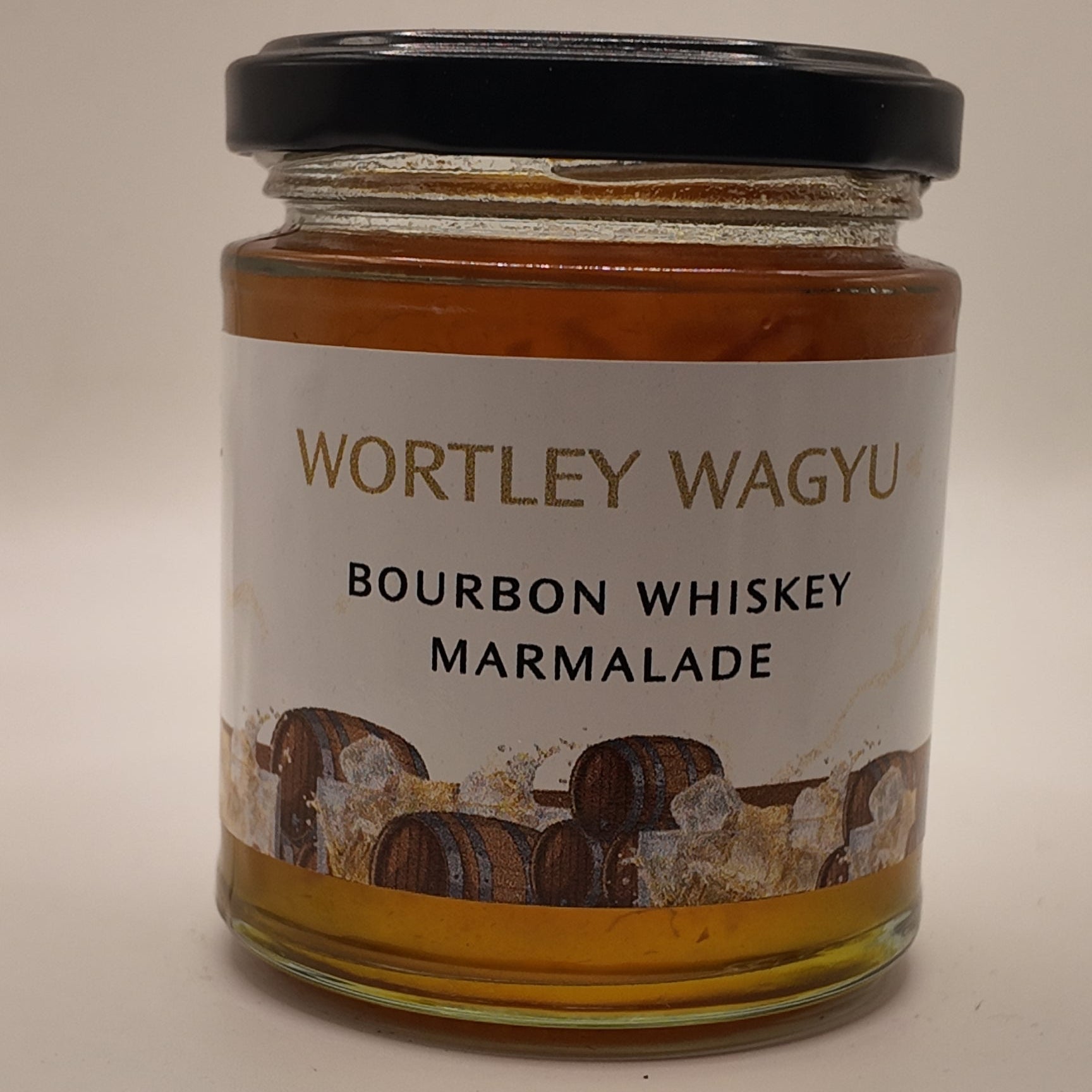 A glass jar of Wortley Wagyu Bourbon Whiskey Marmalade with a black lid and a white label, set against a plain light beige background.